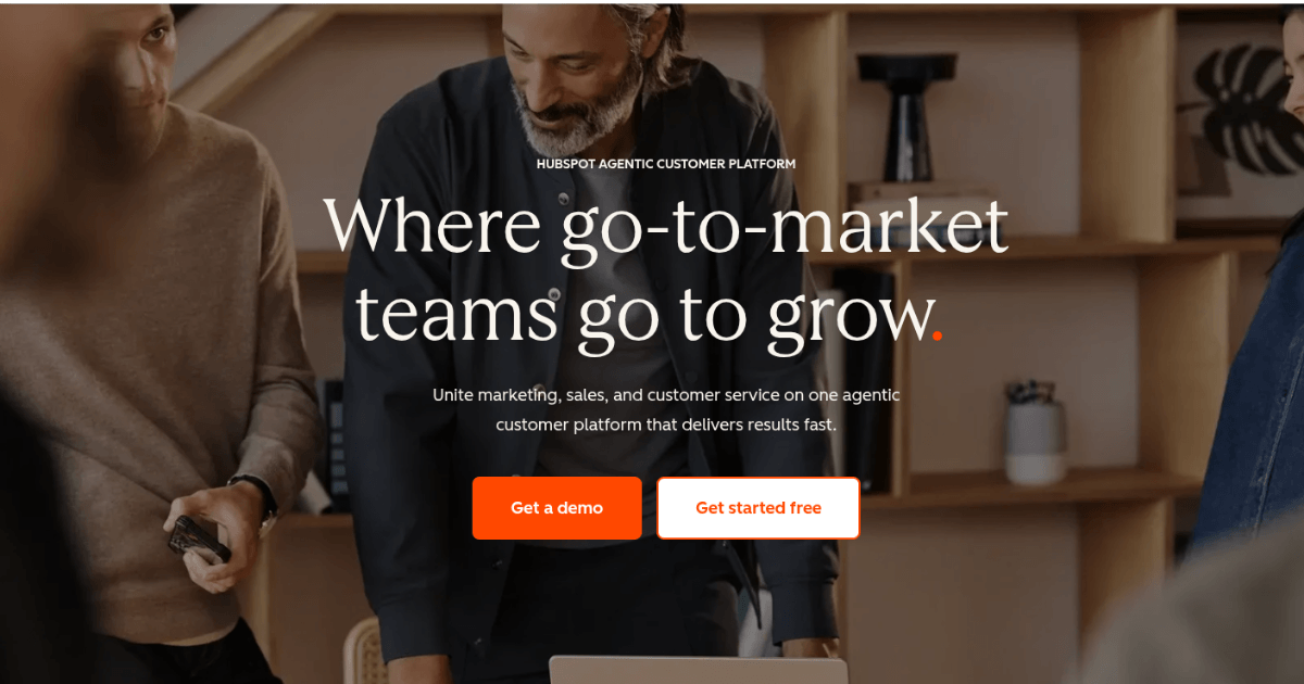 HubSpot Agentic Customer Platform homepage showing team collaboration scene with headline and orange call‑to‑action buttons.